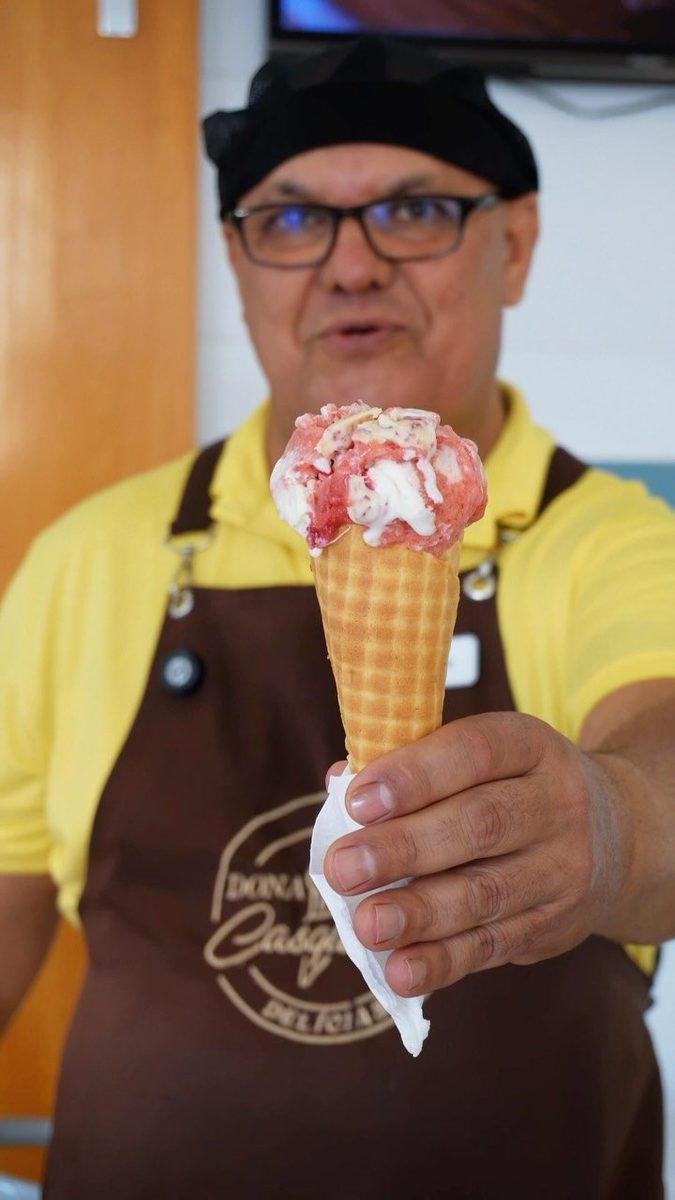 Atendente da Dona Casquinha entregando casquinha com avental estampado da marca